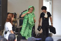 Negiccoオリジナルグッズ「Negi Poncho」を試着する熊倉マネージャー（中央）。