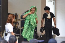 Negiccoオリジナルグッズ「Negi Poncho」を試着する熊倉マネージャー（中央）。