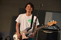 ネギ色のボトムスに「NEGiFES」Tシャツを合わせた“ネギセラトップス”のベーシスト林幸治。