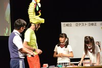 流暢な英語でジョセフ・テイムと会話する日高麻鈴と、その横で黙々と作業を続ける吉田爽葉香。