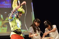 ジョセフ・テイムのサポートを受けながら「ラックンゴックン」を組み立てる岡崎百々子と大賀咲希。