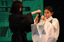 切った髪を筆にくくり付ける菅えみり。