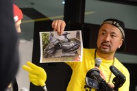 修理前のスクーターの写真を見せる「MUTOMA」スタッフ。