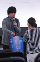 クイズに正解して感激するファンにサイン入りポスターを手渡しする秦基博。