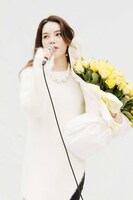 黄色いバラの花束を抱えて歌う安田レイ。