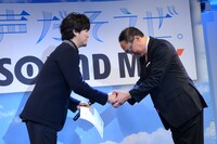 株式会社エクシング吉田篤司代表取締役社長から賞状とトロフィーを受け取る秦基博。