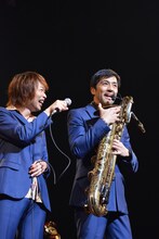 バリトンサックスのマイクを使って話す谷中敦（右）。