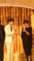 握手を交わす星野源（左）と総合司会の有働由美子アナウンサー（右）。
