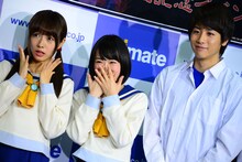 カメラマンのリクエストに応えたあと、照れ笑いを浮かべる生駒里奈（中央）。