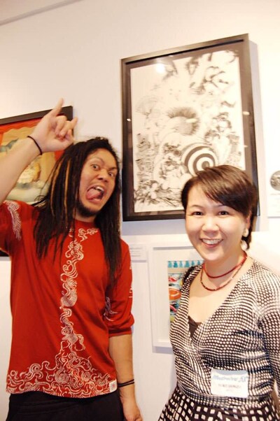 原画をバックに記念撮影するマキシマムザ亮君とYuko Shimizu。