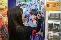 とらのあな秋葉原店Bのエレベーターの扉にサインする上坂すみれ。