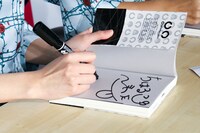 「がめつくストロング～毒舌OLラッパー、世間をぶった斬る！～」にサインを入れるゴンチ。