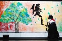 美術部のイラストに「優しさ」の文字を添える欅坂46書道部・尾関梨香。（写真提供：Sony Music Records）