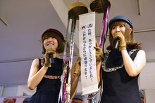 くす玉のメッセージを見せるレナ（左）とリサ（右）。