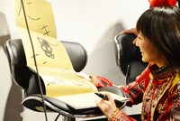 ツアーパンフレットにサインを書き込む百田夏菜子。