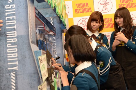 陳列用ポップにサインを書き入れる欅坂46メンバー。