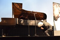 MCにピアノ演奏を促され「これは一体なんでしょう」とピアノをのぞき込む坂本龍一。