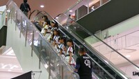 エスカレーターで上の階に上がるばってん少女隊。（写真提供：ビクターエンタテインメント）