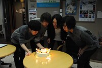 ケーキのロウソクの炎を吹き消すShout it Outの4人。