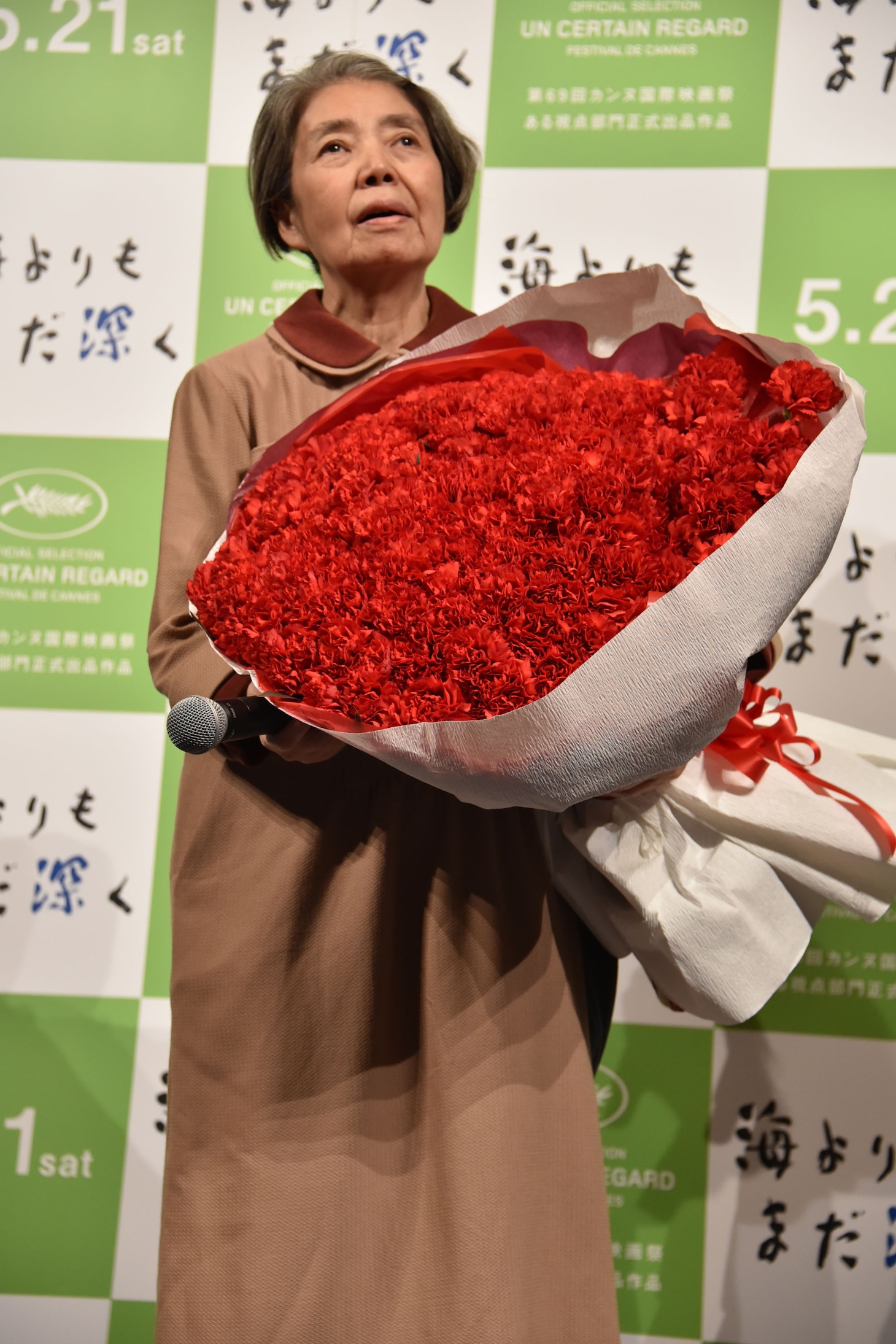 巨大な花束を抱える樹木希林。