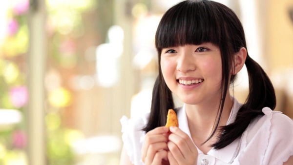 「おむすび名人」のWeb CMのワンシーン。おむすび名人を手に微笑む田中美海。