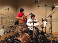 アコースティックギターを演奏する植野隆司（左）とドラムを叩く澤部渡（右）。