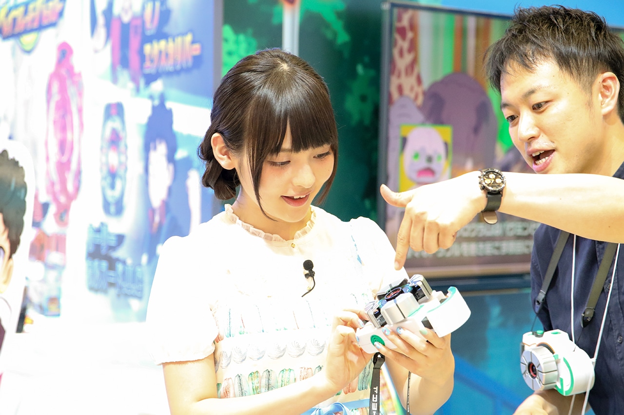 アニメ「カミワザワンダ」の関連アイテム「カミワザショット」の説明を受ける上坂すみれ。