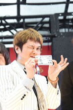 ニセ札を手にウインクするKen Yokoyama。