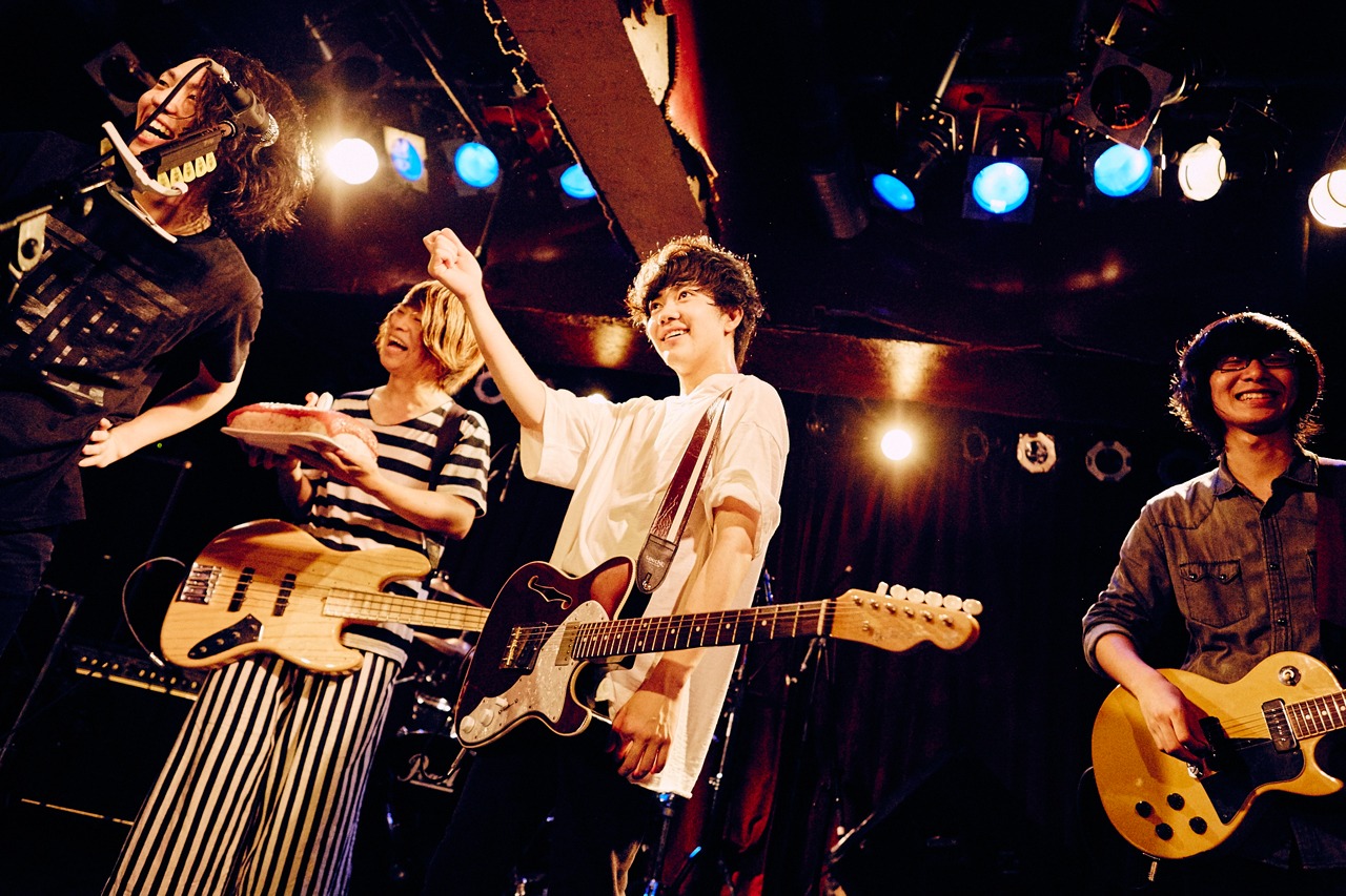 山内彰馬（Vo, G）の誕生日を特大寿司で祝うメンバー。
