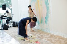 ローラーを使って自身のスニーカーをペイントする柴咲コウ（手前）。（撮影：市川タカヒロ）