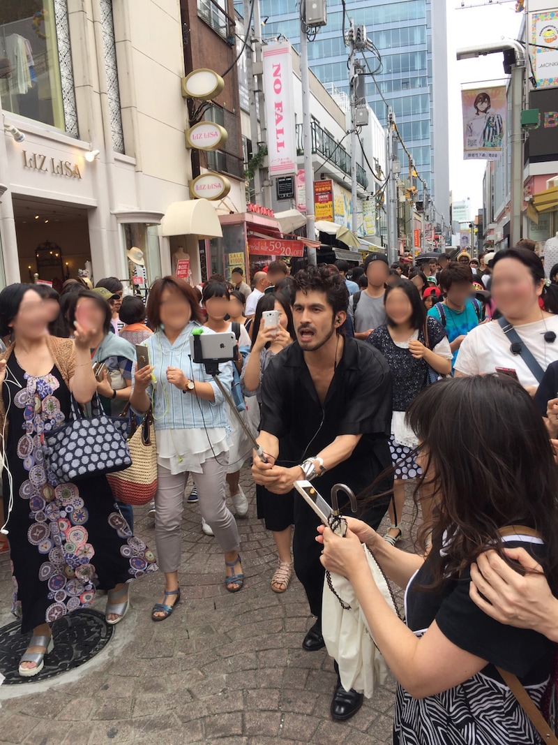 自撮り棒を持って自ら撮影しながら竹下通りを歩く平井堅。