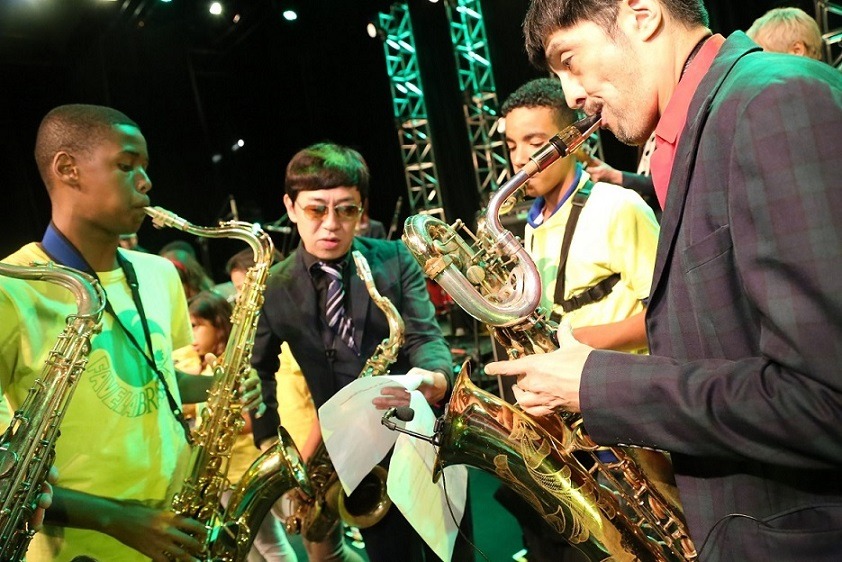 Fabela Brassの子供たちと交流するGAMO（左から2番目）と谷中敦（右）。（写真提供：Sony Music Brazil）