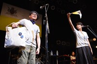 自身もお気に入りのTWEEDEESオリジナルグッズを紹介する沖井礼二（左）と、旗を振って盛り上げる清浦夏実（右）。