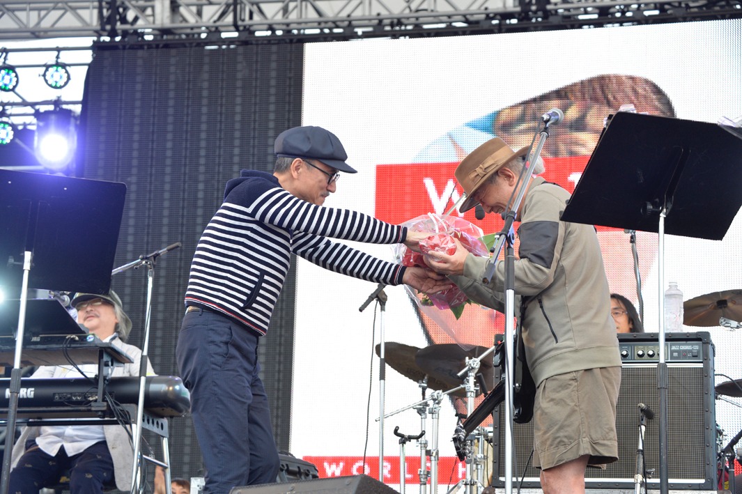 鈴木慶一に花を贈る高橋幸宏（左）と、受け取る鈴木慶一（右）。（Photo by TEAM LIGHTSOME）