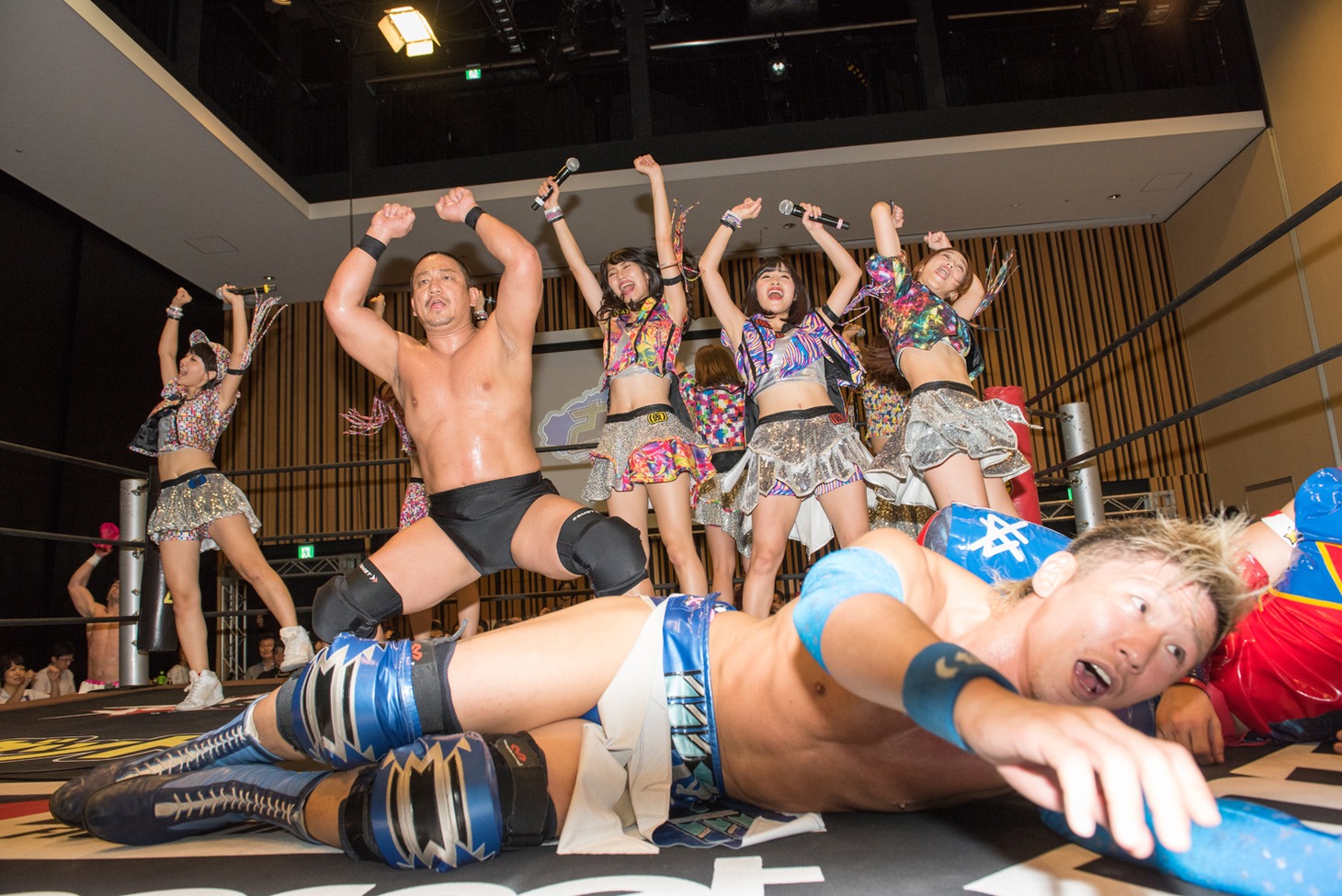 高木三四郎と共に勝利のファイヤーポーズを行うアップアップガールズ（仮）と横たわる大石真翔。