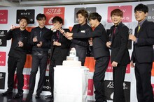 シャンパンの栓抜きに挑戦するタカシ（中央）。