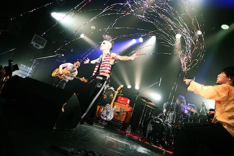 夏目創太（G, Cho）に向けてクラッカーを発射する下川リオ（Vo, G）。（撮影：新倉映見）