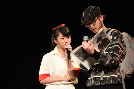 道に迷った外国人（サンディー・カイ / 右）と、古いガイドブックを前に困り顔のmei（左）。