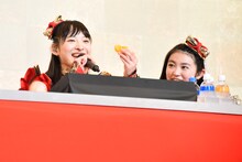 ステージ上でみかんをモリモリ食べる松野莉奈（左）。