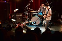 転がりながらベースを弾く稲葉航大（B / Helsinki Lambda Club）を無の表情で見守る橋本薫（Vo, G / Helsinki Lambda Club）とアベヨウスケ（Dr / Helsinki Lambda Club）。（撮影：高田真希子）