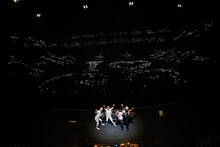 座席占いで大凶を引いた人のまばらな灯りとともに記念撮影するゴールデンボンバー。（撮影：菅沼剛弘）