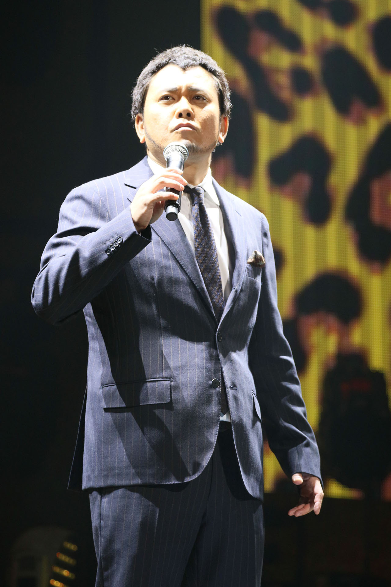 くりぃむしちゅー有田扮する“高田延彦”（PPAPPT統括本部長）。（写真提供：AMC）