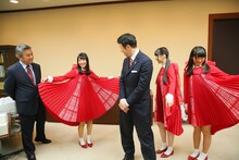 デビューに向けて作られた真っ赤な衣装を米山隆一新潟県知事（中央）にお披露目するNGT48。(c)AKS