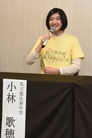 手描きイラストTシャツを説明する小林歌穂。出演メンバー4人と「平和な感じのタンポポ」を描いたという。