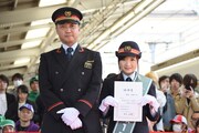 ふじみ野駅長（左）と1日駅長の任命書を掲げる有安杏果（右）。
