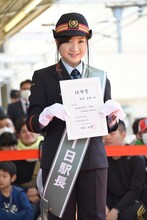 1日駅長の任命書を掲げる有安杏果。