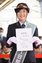 1日駅長の任命書を掲げる有安杏果。