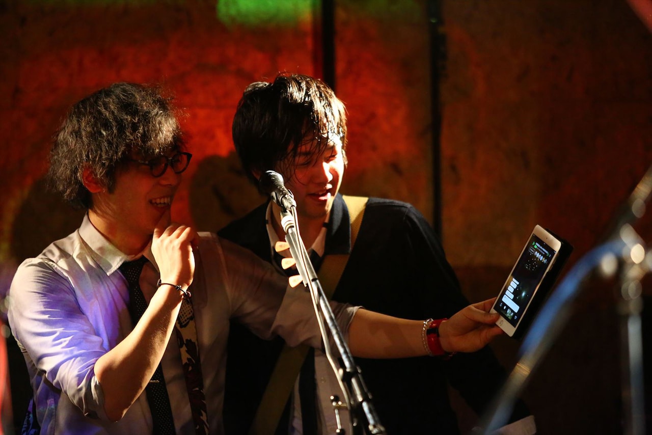 ライブ中にLINE LIVEのコメントを見る三浦隆一（Vo, G）と佐々木直也（G）。（撮影：寒川大輔）