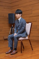 椅子に座る星野源。