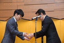 周防正行からモノリスを受け取る星野源。